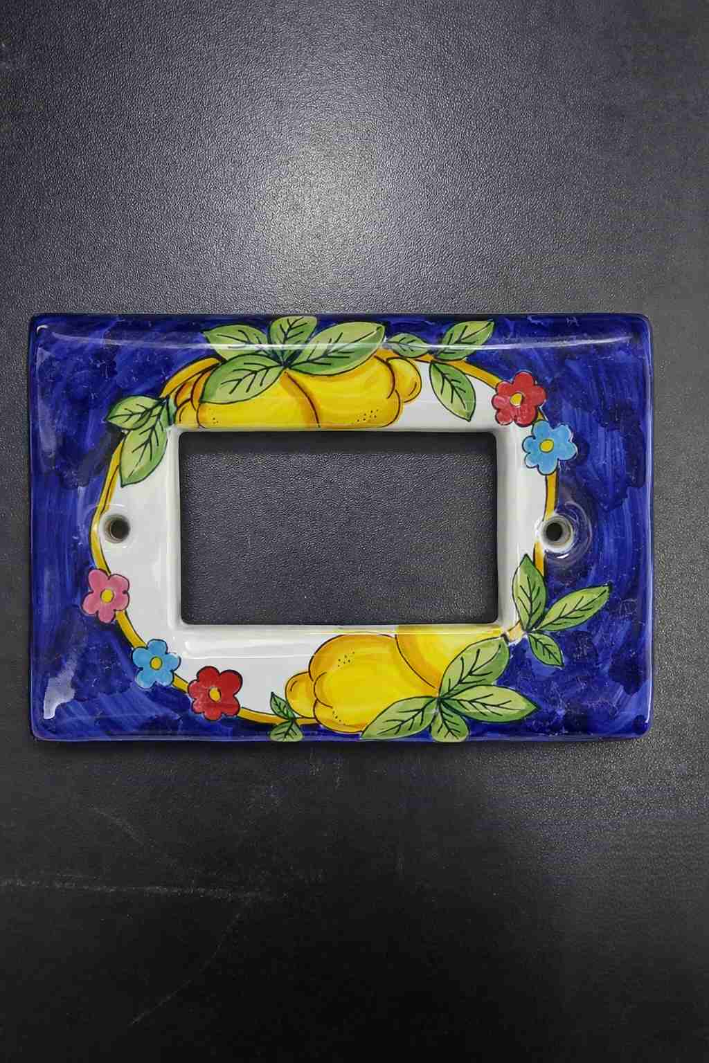 Placca copri interruttore in ceramica modello Matix decorata a mano, con decoro artigianale ispirato ai colori e ai motivi della Costiera Amalfitana.